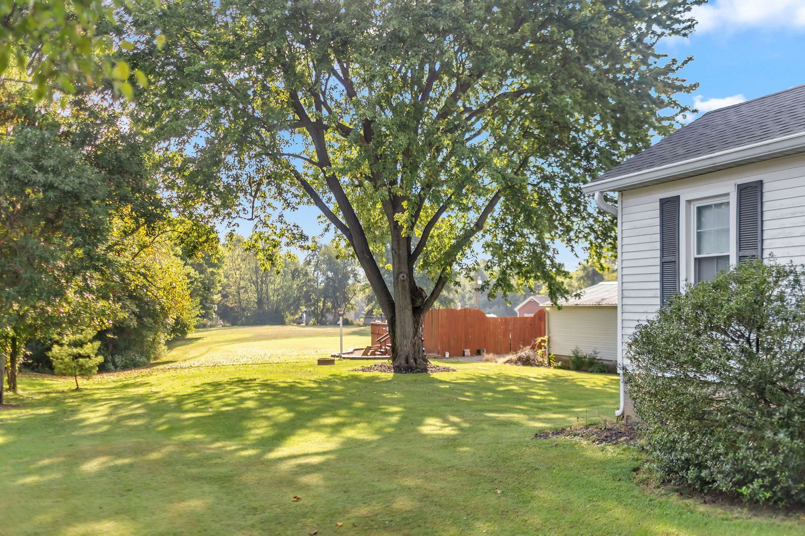 Wide backyard lawn with mature shade trees